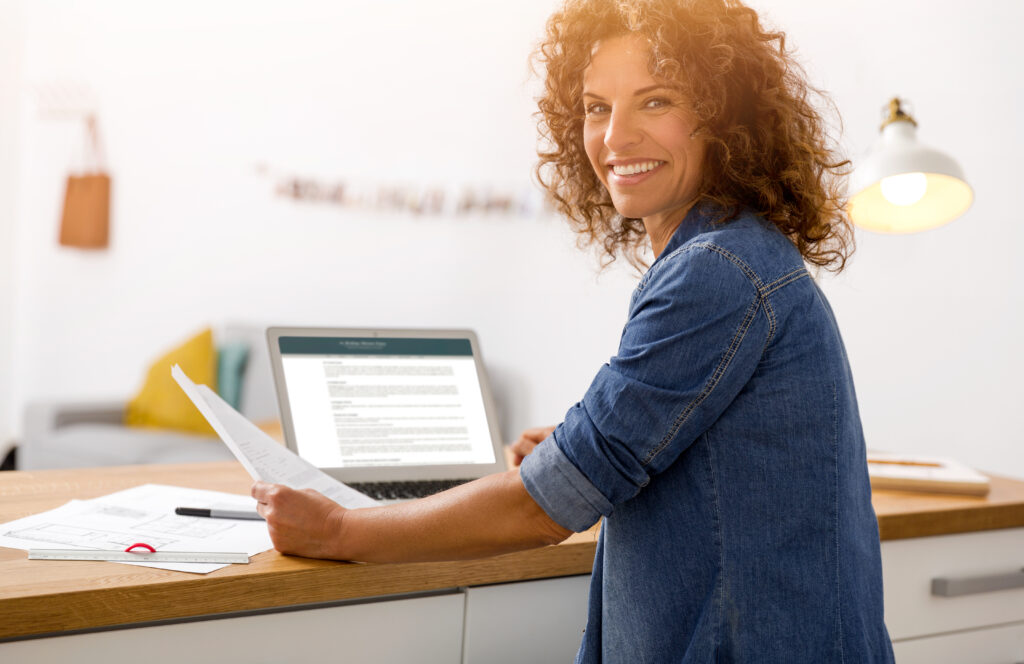 Female Business Owner sitting at a desk smiling while Learning about how to hire and build her team like a boss.